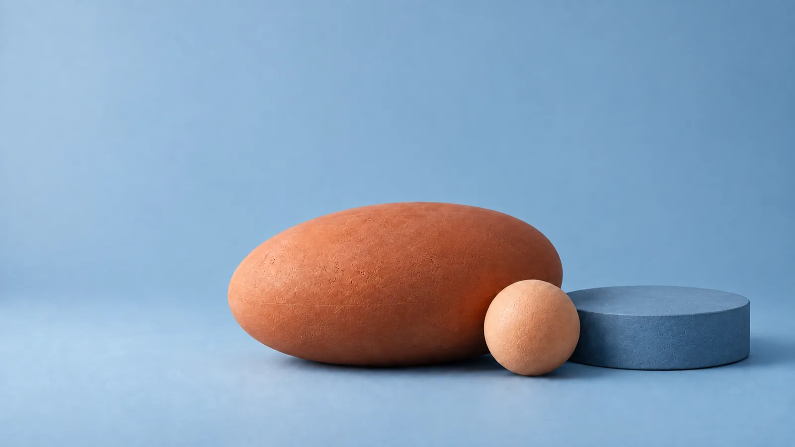 Terracotta ellipsoid, slate-blue cylinder and apricot sphere on a dusty blue backdrop — Blue & Clay from Quiet Forms